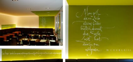 Design of a quote by Churchill and a row of words about enjoying food for a restaurant. Written on the wall spontaneously with a flat brush.