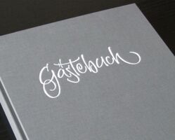 Der Umschlag eines Gästebuches mit eigens dafür hergestelltem Schriftzug, der mittels Heißfolien-Prägedrucks ins Material geprägt wurde.